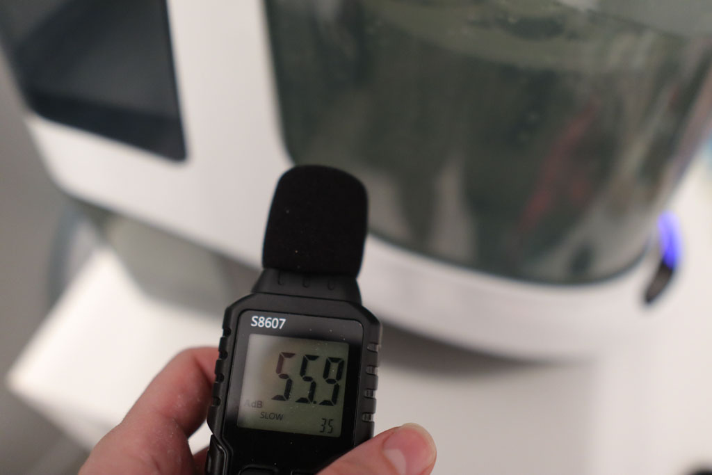 A photo of Dim Nikov, Dad's Picks editor, measuring the level of noise produced by the Baby Brezza Bottle Washer Pro with a sound meter.