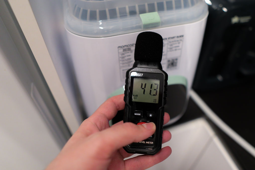 A photo of a sound meter pointed at a baby bottle washer. The meter's reading is 41.3 decibels.